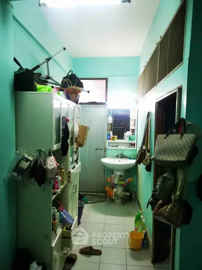 Compact bathroom with teal walls, white cabinets, and a small sink, showcasing efficient storage solutions.