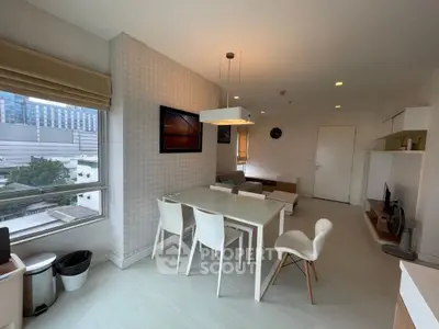 Modern living room with dining area and large window view in urban apartment.