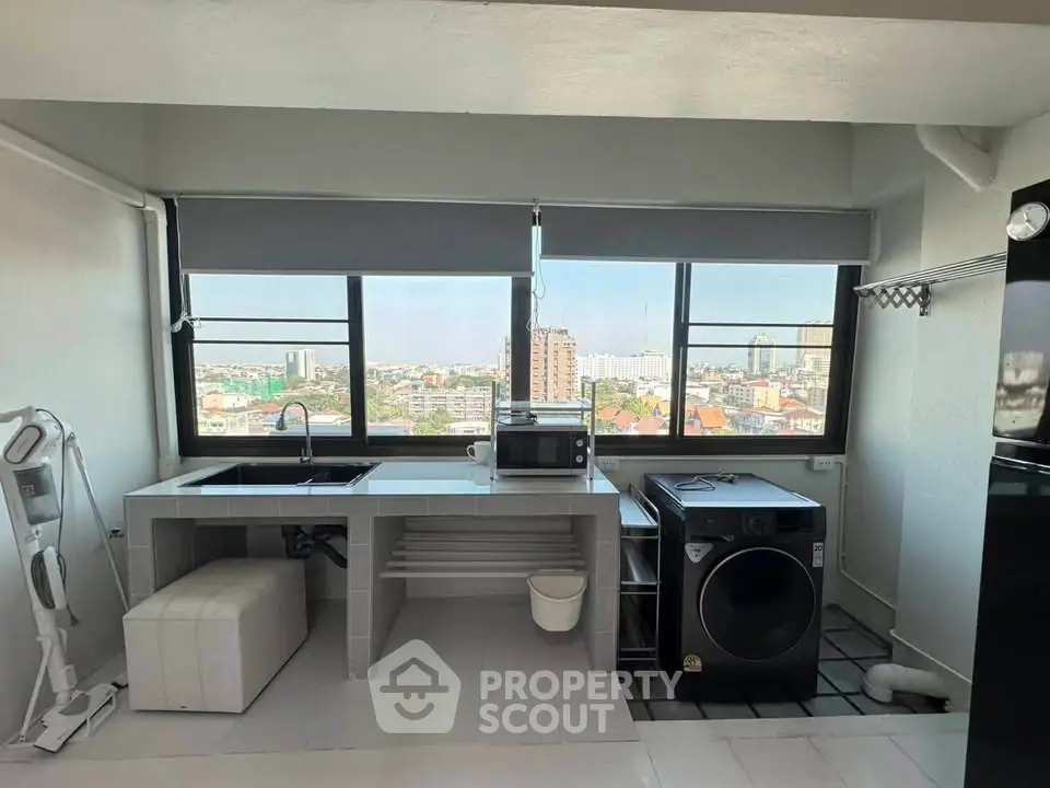 Modern kitchen with city view, featuring washing machine and microwave, ideal for urban living.