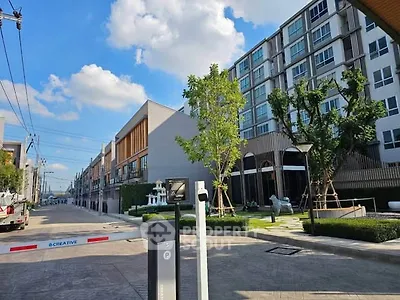Modern residential building with lush landscaping and clear blue sky, showcasing contemporary urban living.