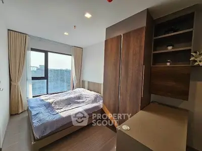 Modern bedroom with large window and stylish wooden furniture in a high-rise apartment.