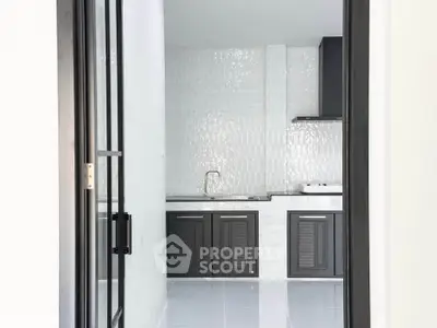 Modern kitchen with sleek black cabinets and glossy white tile backsplash.