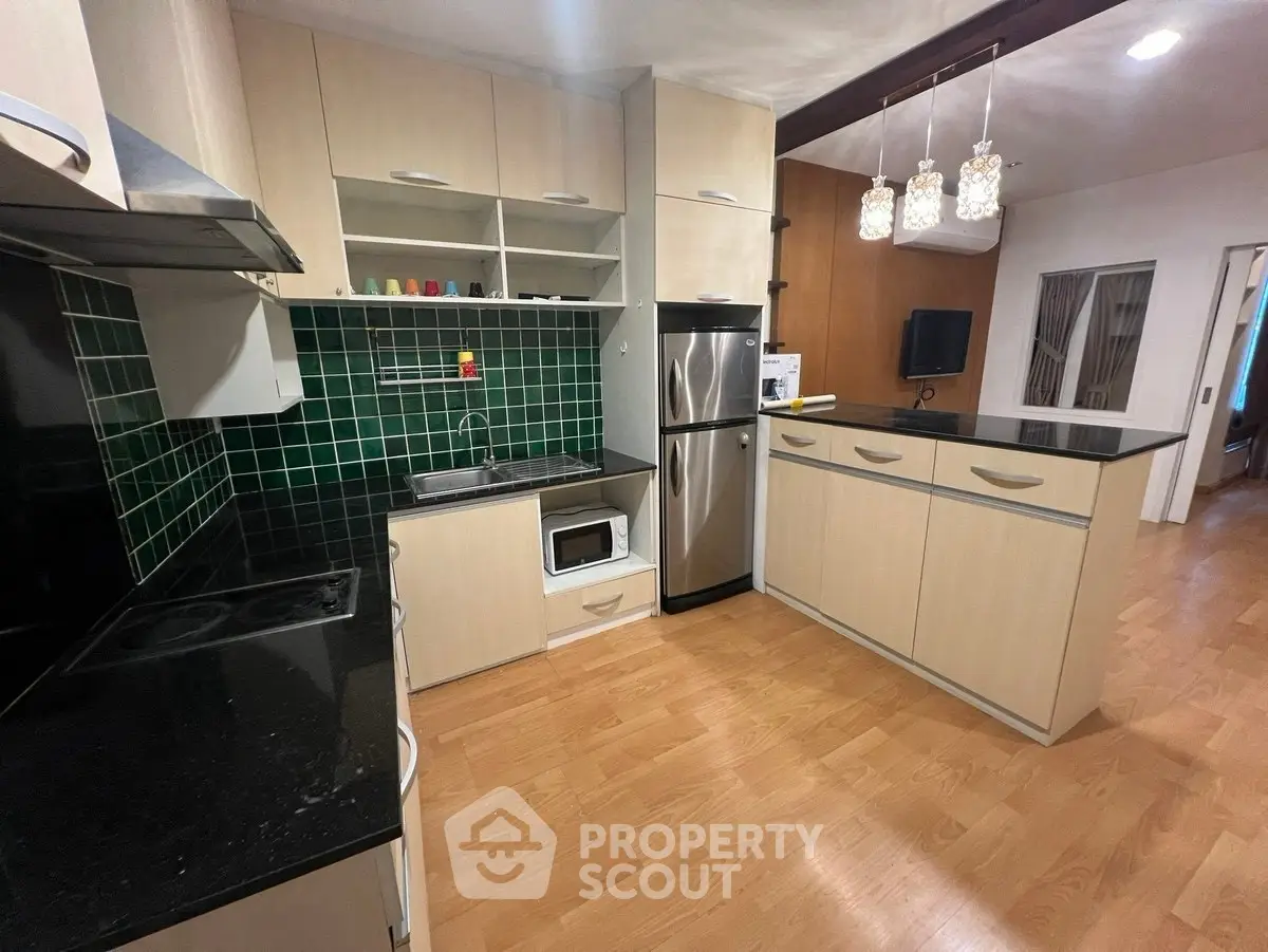 Modern kitchen with open layout, stainless steel appliances, and stylish green tile backsplash.
