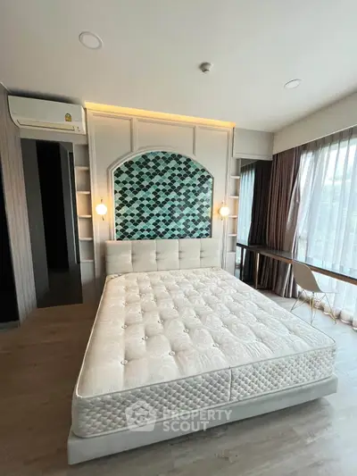Spacious bedroom with stylish accent wall and large windows offering natural light.