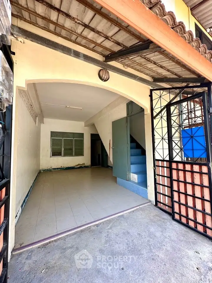 Charming townhouse entrance with tiled flooring and staircase, perfect for renovation.