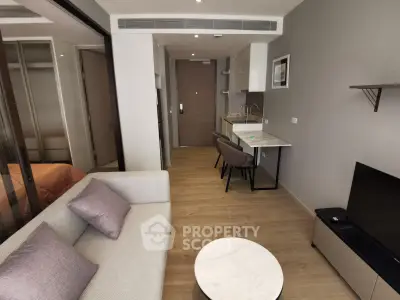 Modern studio apartment with cozy living area and compact kitchen, featuring stylish furniture and wooden flooring.