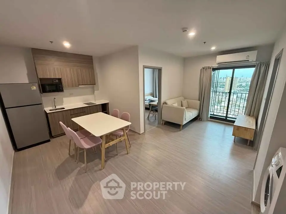 Modern open-plan living room with kitchen and balcony view in a high-rise apartment.