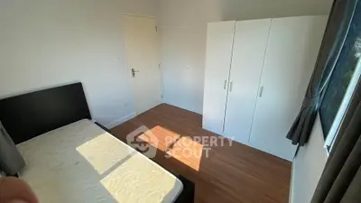 Bright minimalist bedroom with wooden flooring and large wardrobe