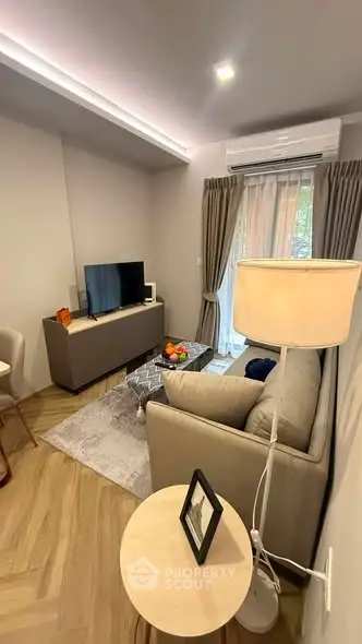 Cozy living room with modern decor and natural light, featuring a comfortable sofa and flat-screen TV.