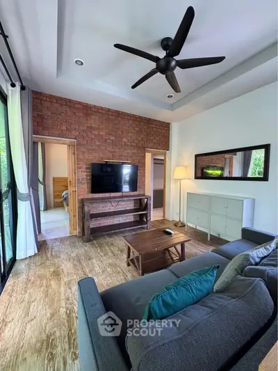 Charming living room with rustic brick wall, modern ceiling fan, and cozy seating area.