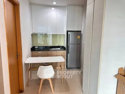 Modern kitchen with sleek cabinets and dining area in compact apartment
