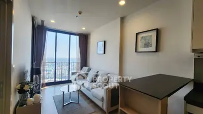 Modern living room with large windows offering stunning city views, featuring elegant decor and cozy seating.