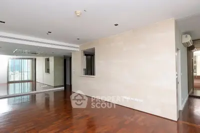 Spacious modern living room with wooden flooring and large windows offering natural light.