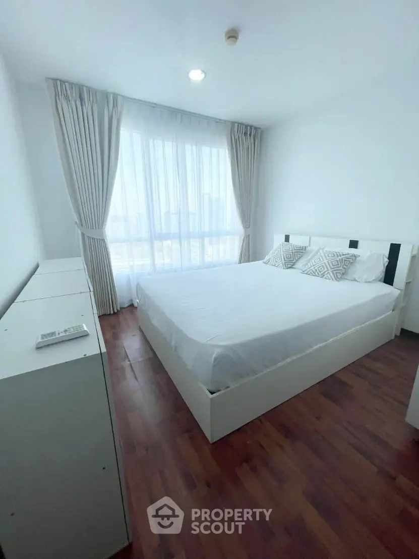 Bright and airy bedroom with large window and modern furnishings, perfect for relaxation.