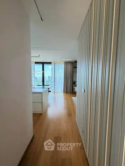 Spacious modern apartment hallway leading to a bright living room with city views.
