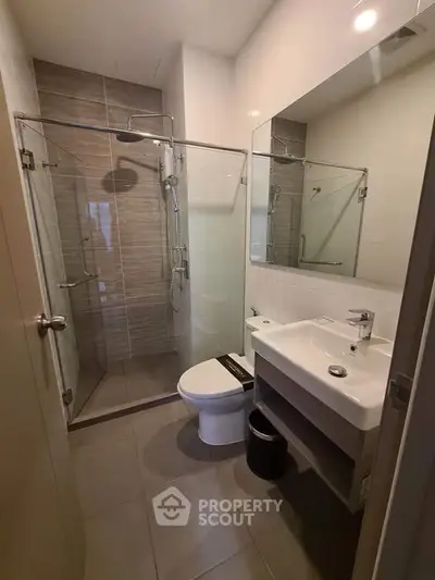 Modern bathroom with glass shower and sleek fixtures in contemporary apartment.