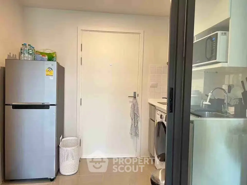 Modern kitchen with stainless steel fridge and washing machine in compact layout.