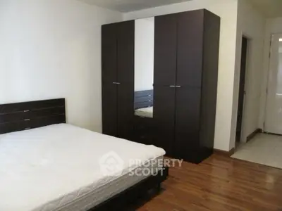 Spacious bedroom with modern dark wood furniture and hardwood floors.