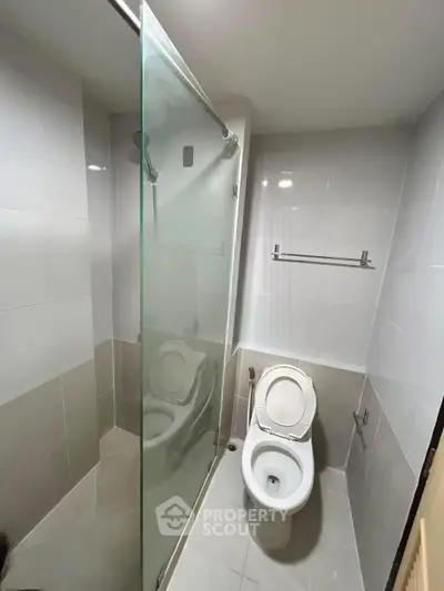 Modern bathroom with glass shower and sleek fixtures in a compact space.