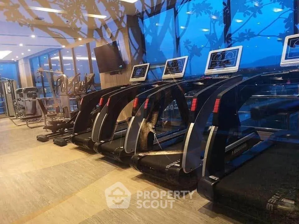 Luxurious gym with modern treadmills and panoramic views in upscale residential building.