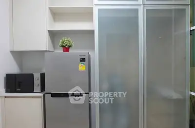 Modern kitchen with sleek fridge and microwave in minimalist design.