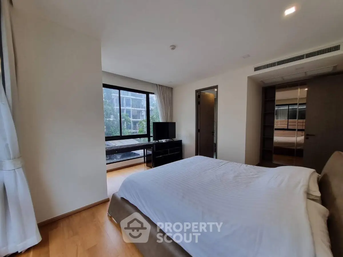 Spacious bedroom with large windows and modern decor in a luxury apartment.