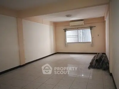 Spacious empty room with tiled floor and air conditioning, ideal for customization.