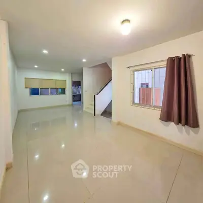 Spacious open-plan living room with tiled flooring and staircase, ideal for modern family living.