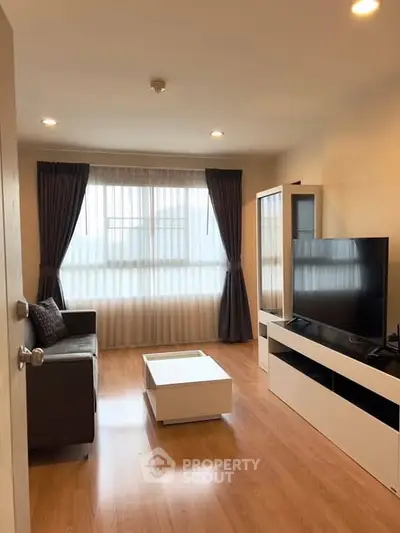 Modern living room with large window, sleek furniture, and wooden flooring.