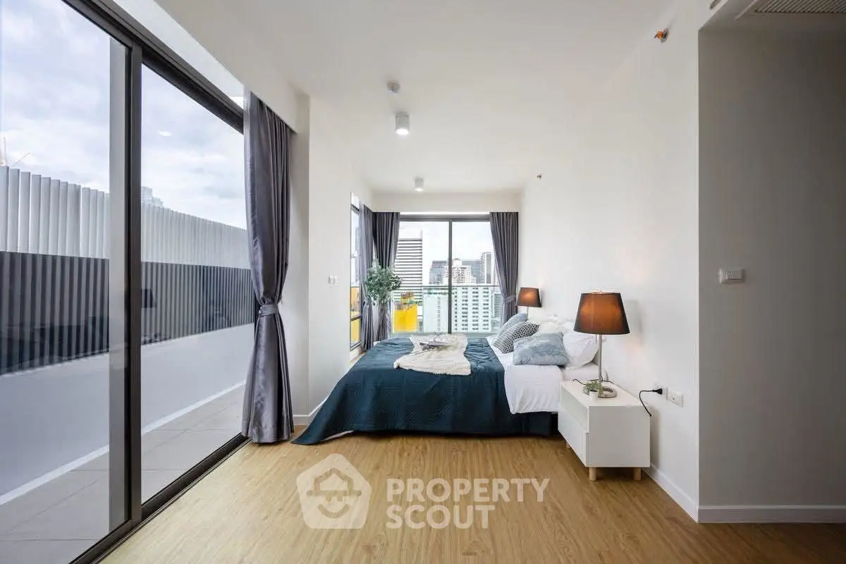 Modern bedroom with large windows and city view, featuring stylish decor and natural light.