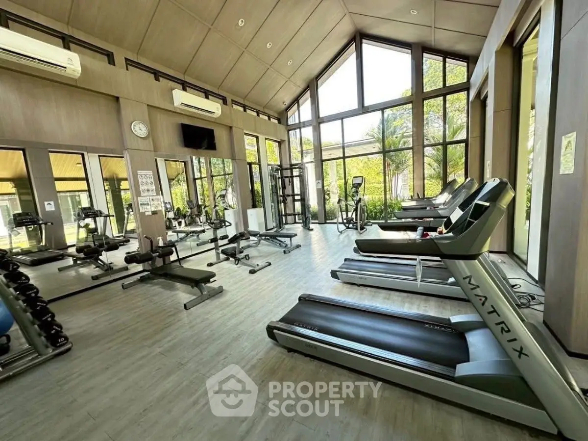 Spacious modern gym with large windows and state-of-the-art equipment in a luxury real estate property.