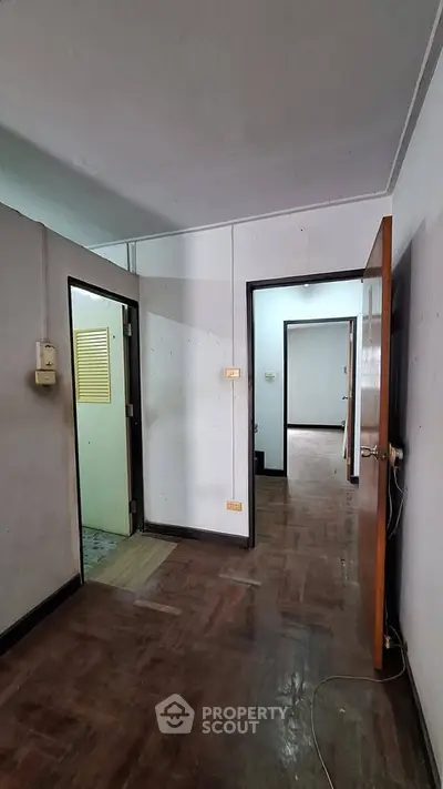 Spacious interior hallway with wooden flooring and open doors leading to multiple rooms.
