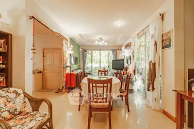 Charming living room with elegant dining area and large windows offering lush garden views.