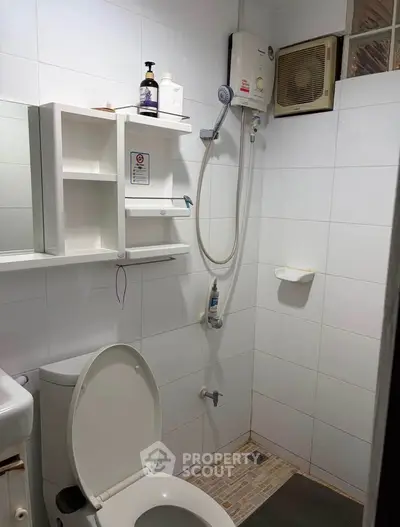Compact bathroom with shower, toilet, and wall-mounted storage in a modern apartment.