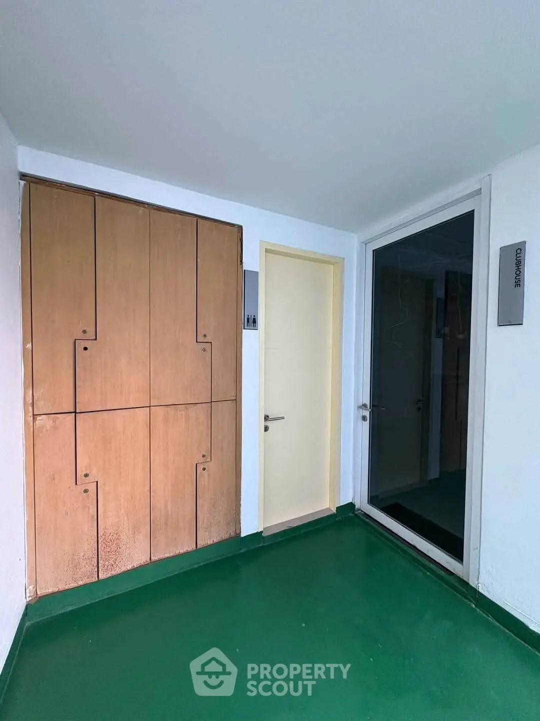 Modern apartment entrance with green flooring and wooden storage cabinets.