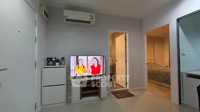 Modern living room with TV, air conditioning, and view into bedroom and bathroom.