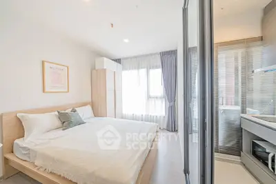 Bright and modern bedroom with large windows and sleek kitchen area, perfect for urban living.