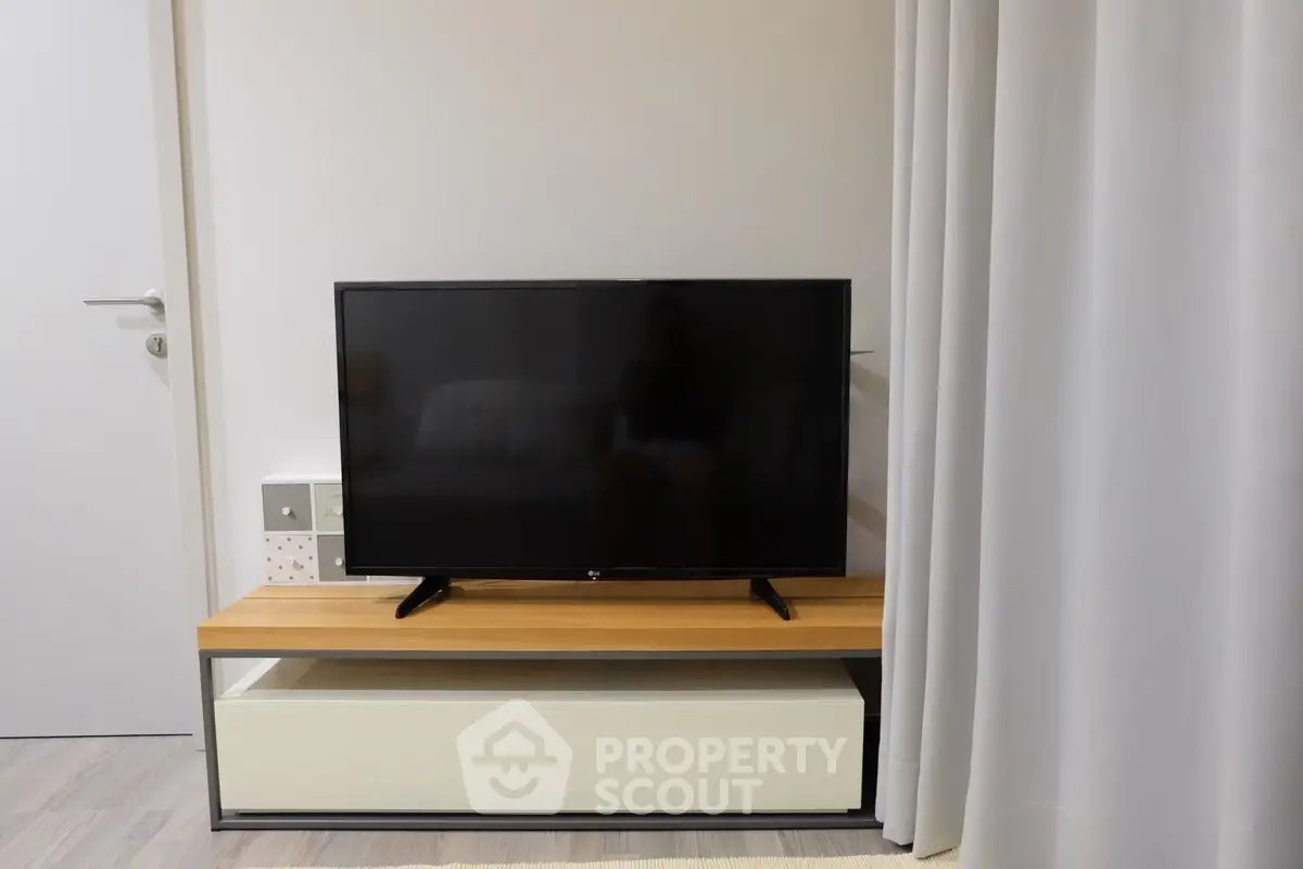 Modern living room with sleek TV setup on wooden stand, perfect for cozy entertainment.