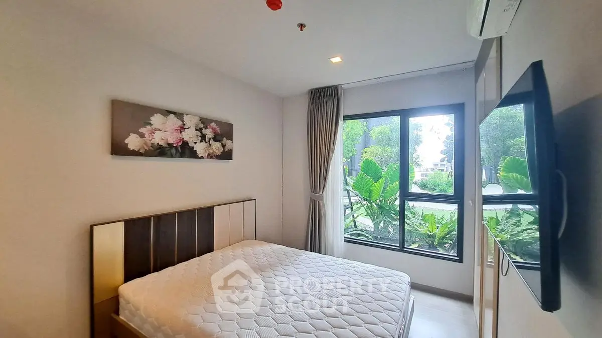 Cozy bedroom with large window and modern decor in a serene setting.