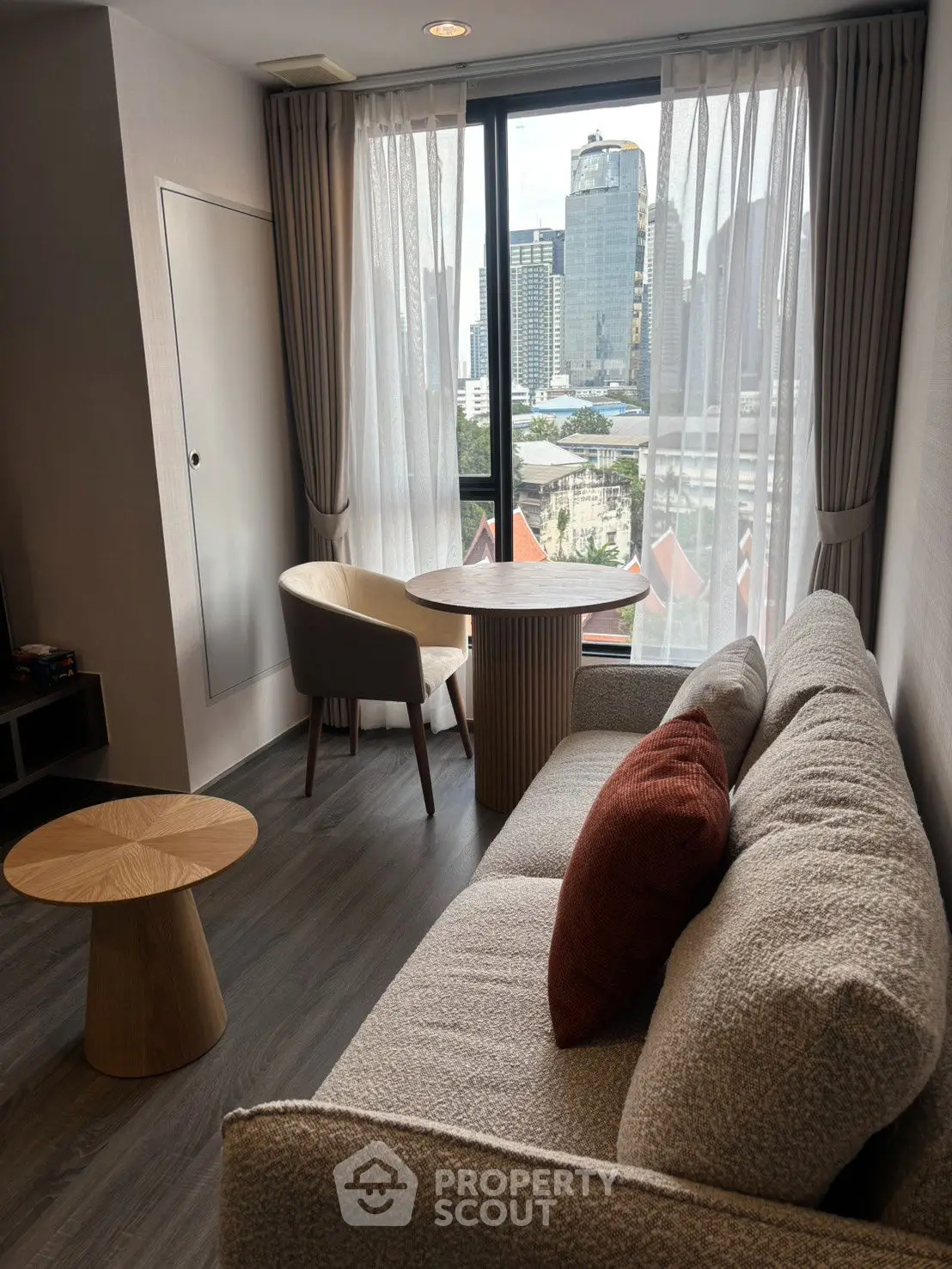 Modern living room with city view, stylish furniture, and large window.