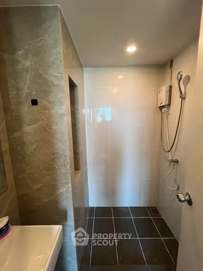 Modern bathroom with sleek tiles and built-in shower heater, perfect for a contemporary home.