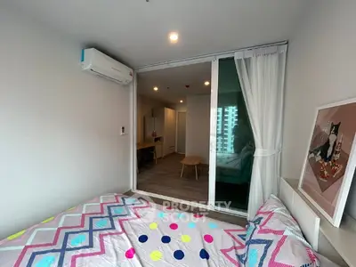 Modern bedroom with colorful bedding and air conditioning, featuring a view into a stylish living area.