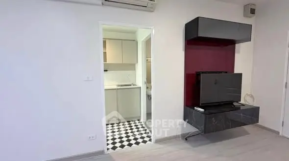 Modern living room with wall-mounted TV and view into stylish kitchen