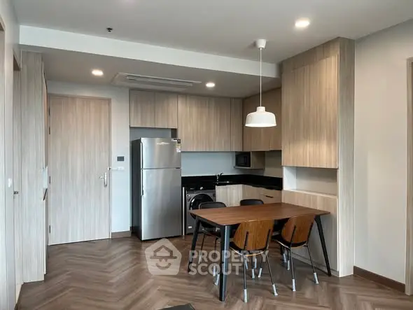 Modern kitchen with dining area, featuring sleek cabinetry and stainless steel appliances.