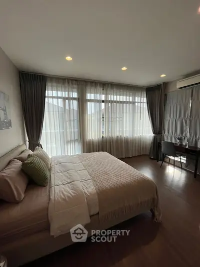 Spacious bedroom with large windows and elegant decor in modern apartment