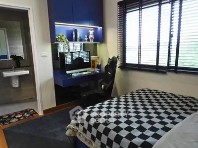 Modern bedroom with study area featuring a sleek desk and computer setup, adjacent to a stylish bathroom.