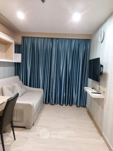 Cozy living room with modern sofa and wall-mounted TV, featuring elegant blue curtains.