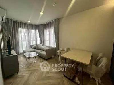 Modern living room with elegant decor and natural light, featuring a cozy sofa and dining area.