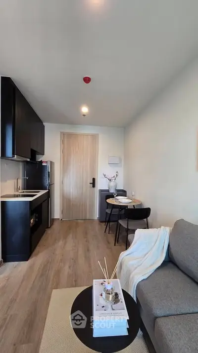 Modern living room with open kitchen, stylish decor, and cozy seating area in a contemporary apartment.