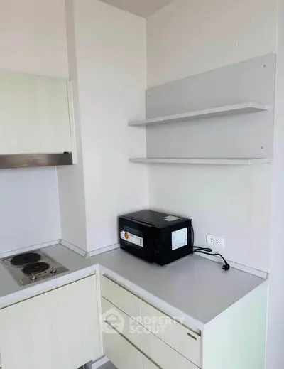 Modern kitchen corner with microwave and electric stove in minimalist design.